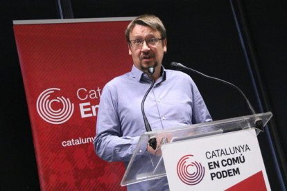 El jefe de filas de los comunes en el Parlament, Xavier Domènech, con el logo del partido de fondo.