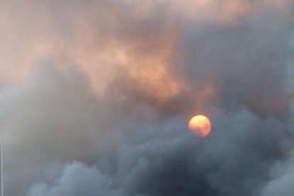 Una columna de fum espès i negre tapa el sol per sobre de la nau del Grup Balfegó en ple incendi.