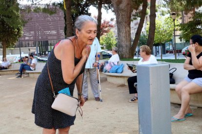 Una mujer intentando refrescarse en una fuente pública.