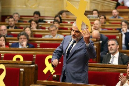 El diputat de Cs, Carlos Carrizosa, retirant un llaç del banc dels consellers al Parlament.