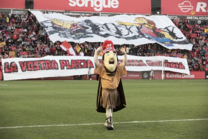 La mascota del Nàstic, amb les pancartes de fons.