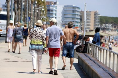 Plan general de varios turistas paseando por el paseo marítimo de la playa de la Pineda, en Vila-seca, el 9 de mayo del 2018