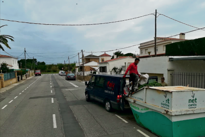 Operaris d'una empresa de jardineria buidant les restes a un contenidor de Cambrils.