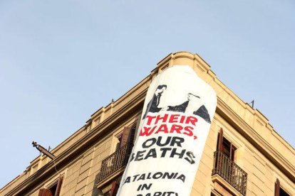 Una pancarta despenjada al Pla de l'Ós, davant el mosaic de Miró de la Rambla, resa: «Les seves guerres, els nostres morts. Catalunya en solidaritat amb les víctimes».