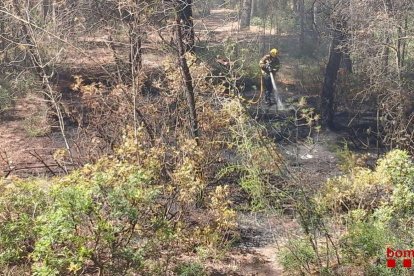 Un bombero remojando la zona quemada en el barrio de Sant Salvador.