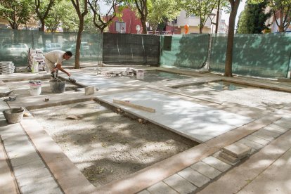 Un operari realitza feines a la font, a la part central de la plaça.