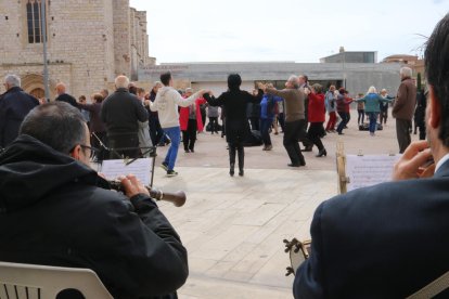 Diverses persones ballant sardana a Montblanc i dos músics de la cobla.