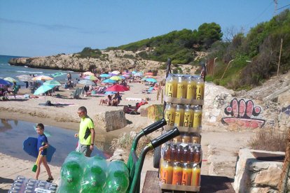 Botelles de refrescos d'un repartidor sobre una arqueta i, a la dreta, aspecte que ofereix la tanca metàl·lica del ferrocarril.