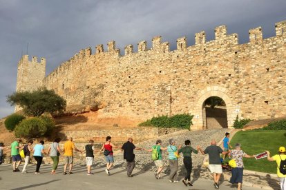 Diverses persones ballant una sardana tot encerclant la muralla de Montblanc.