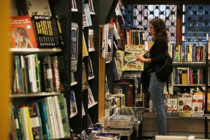 Una dona observa diversos llibres a la llibreria Galatea de Reus.