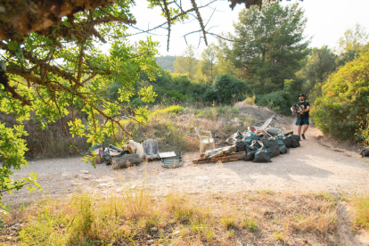 En primer terme, restes recollides la setmana passada i, al fons, un dels joves participants.