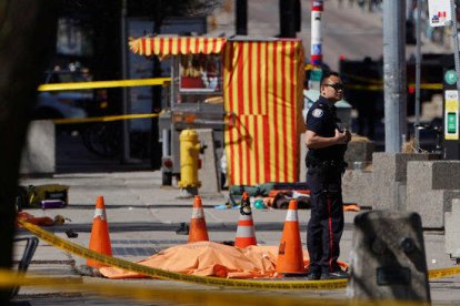 Un agent de policia al costat d'una de les víctimes d'un atropellament múltiple d'una furgoneta a Toronto, al Canadà.