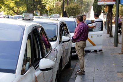 Pla obert d'una filera de taxis en una parada de Tarragona, amb alguns conductors xerrant fora dels vehicles. Imatge publicada el 28 de juny del 2018