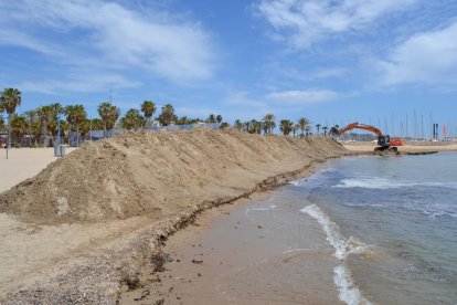 Una excavadora sacando arena de la playa de Ponent, en la zona de la base náutica.