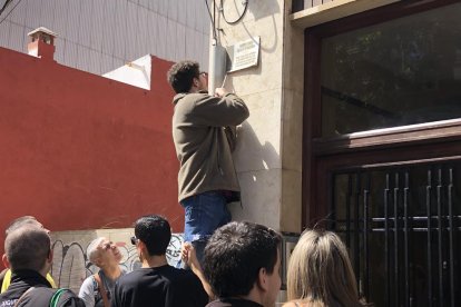 Pla obert d'un home retirant una placa franquista d'un immoble de Reus l'1 de maig del 2019