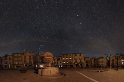 Plano general de la plaza Major de Prades a oscuras, bajo el cielo estrellado.