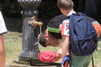 Un joven refrescándose a una fuente en Barcelona.