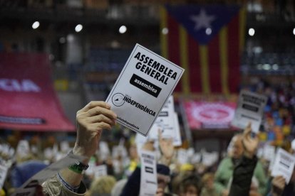 Imagen de los socios de la entidad alzando papeletas para votar.