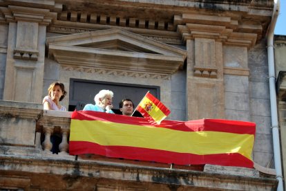 Unas personas exhiben una bandera española en un balcón.