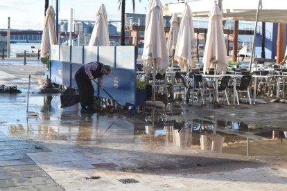 Un treballador d'un restaurant del Carrer Trafalgar netejant la terrassa.