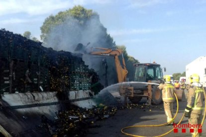 Varias dotaciones de los Bomberos remojando la carga de limones del camión.