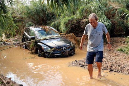 Celestino, caminando descalzo por la riera de Maspujols con su vehículo embarrancado en el fondo, que tuvo que abandonar por el aumento del caudal.