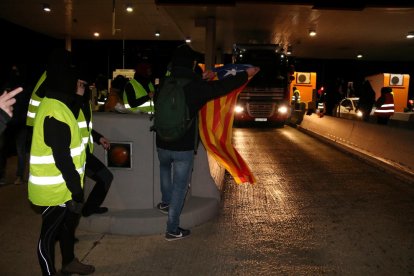 Plan|Plano general del miembros del CDR con una estelada|estrellas saludando los vehículos en el levantamiento de las barreras del peaje del AP7 a la altura de l'Hospitalet de l'Infant en el Baix Camp. Imagen del 9 de diciembre del 2018 (Horizontal).