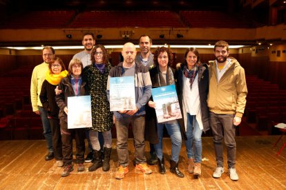 Foto de grup dels integrants de la iniciativa ciutadana de la Riuada Solidària de l'Espluga de Francolí, amb els cartells promocionals del programa d'actes solidaris 'Riumuntada', al teatre del Casal. Imatge del 14 de novembre del 2019