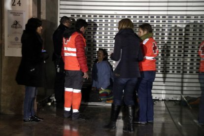 Pla obert de voluntaris de la Creu Roja i de membres de Serveis Socials atenent un sensesostre que dorm a l'entrada d'una botiga del carrer Unió de Tarragona. Imatge de l'11 de gener del 2018