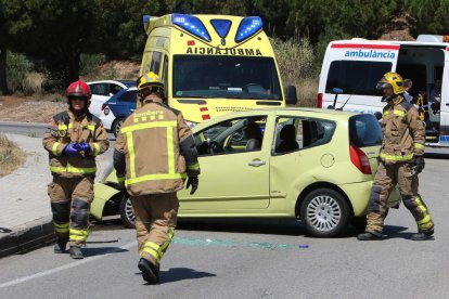 Imatge dels Bombers treballant en l'accident junt al cotxe que ha patit la col·lisió.