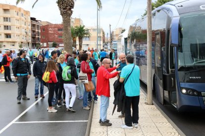 Plano general de la cola de personas esperando subir a los buses organizados por la ANC en Amposta.