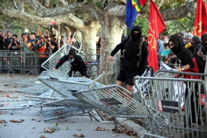 Un grupo de manifestantes tiran las vallas que protegen el acceso al Parlament.