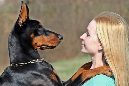 Una mujer con su perro de la raza Doberman.