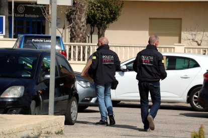 Dos agentes de los Mossos D'Esquadra llevando cajas de documentación que han requisado al Ayuntamiento de Deltebre a un vehículo policial.