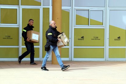 Plano general de dos agentes de los Mossos d'Esquadra con cajas saliendo del Ayuntamiento de Deltebre.