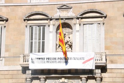 «Libertad presos políticos y exiliados», dice la nueva pancarta con un lazo blanco con una franja roja, en vez del lazo amarillo de la pancarta anterior.