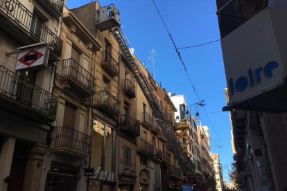 Els Bombers treballant en la façana de l'edifici.