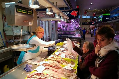 Claustra Bonachí entrega a María Cruz el peix adquirit, mentre Alba Abril espera el seu torn.