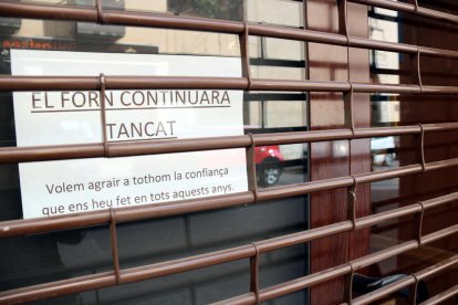 Plano detalle del horno de pan Batet de Reus, una panadería artesana que ha bajado la persiana definitivamente, con un cartel informando a los clientes de su cierre.