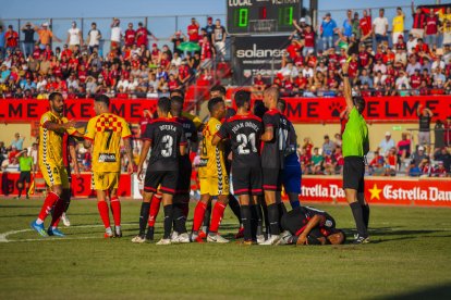 El árbitro del derbi Reus-Nàstic muestra una cartulina a un jugador del conjunto grana.