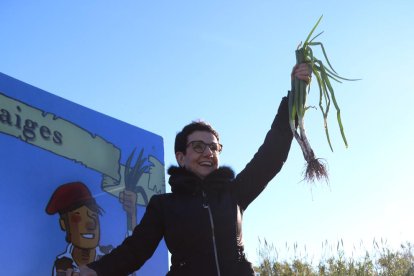 Carme Ruscadella alçant un calçot en l'arrencada simbòlica de la primera ceba dolça de la temporada en la 5a Jornada Gastronòmica de Valls.