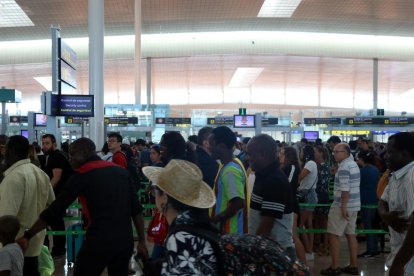 Varias personas haciendo cola al control de seguridad de salida de la T-1 del aeropuerto de Barcelona.