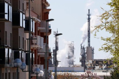 Un bloc d'habitatges de la Canonja, al Tarragonès, amb xemeneies i torxes del complex petroquímic nord al fons.