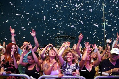 Asistentes a un concierto del Festival Cruce|Encrucijada bajo una lluvia de papeles lanzada desde un escenario.