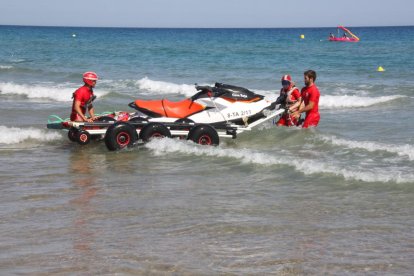 Els socorristes de la Creu Roja entrant la moto aquàtica a l'aigua, a la platja de l'Arrabassada de Tarragona.