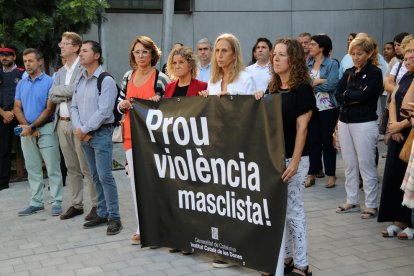 Personas concentradas y la pancarta desplegada durante el minuto de silencio para recordar a la mujer muerta en manos de su hijo en Tortosa.