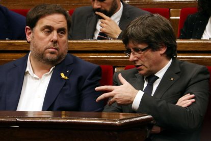 El president de la Generalitat, Carles Puigdemont, parla amb el vicepresident, Oriol Junqueras, al Parlament.