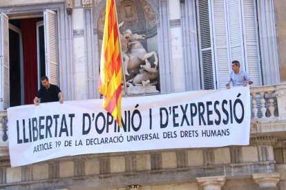 Miembros del equipo del presidente del Gobierno, Quim Torra, colocan la nueva pancarta en la fachada de Palau.