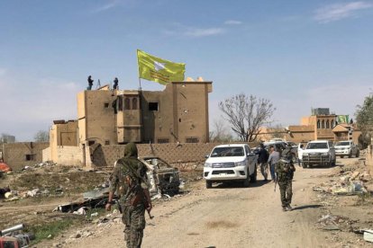 Una bandera de las Fuerzas de Siria Democrática ondea en un edificio dañado de Baghouz.