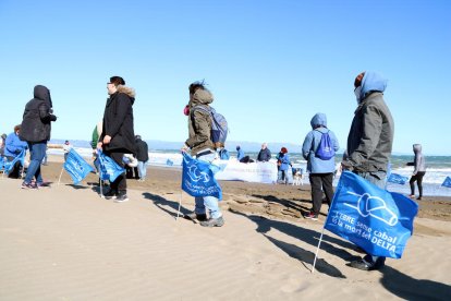 Els ecologistes al costat de les banderes que han col·locat a la platja de la Marquesa per visualitzar la regressió del delta de l'Ebre.